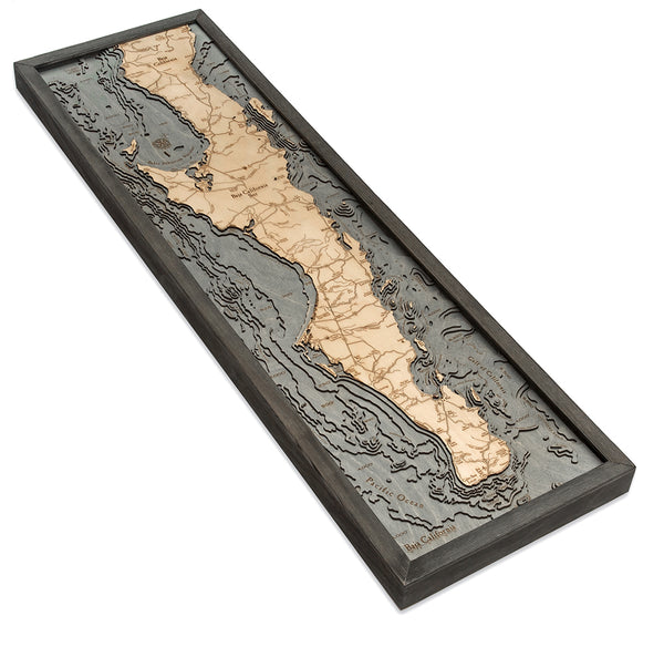 3-D Wood Chart of Baja Peninsula using dark blue and light colored wood in black frame with white background being laid down