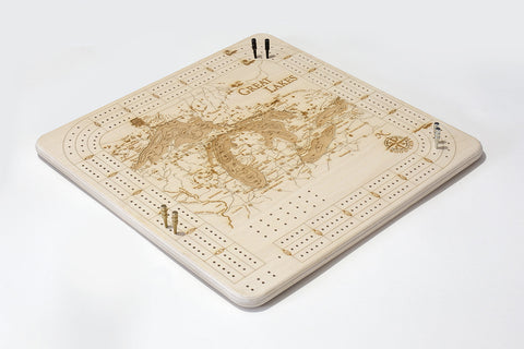 Great Lakes cribbage board laying flat with pegs on it on white background